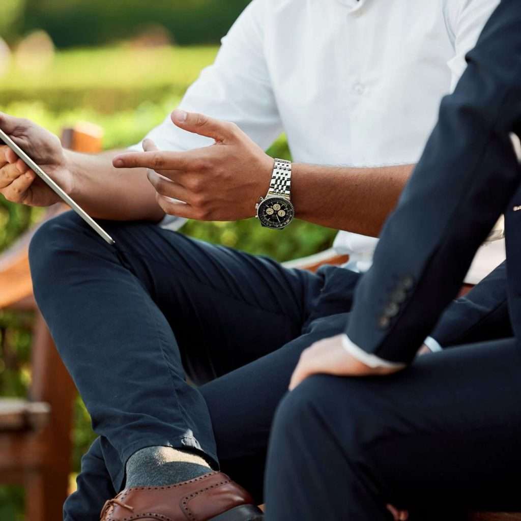 Two people sitting on a bench going through a document on a tablet signifying growth and development. For the RTS Academy "Developing Your People" and "People Development Fundamentals" course.