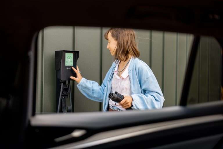 A woman looking about to plug in her electric vehicle. This is a title image for our RTS Academy course on EV Ownership