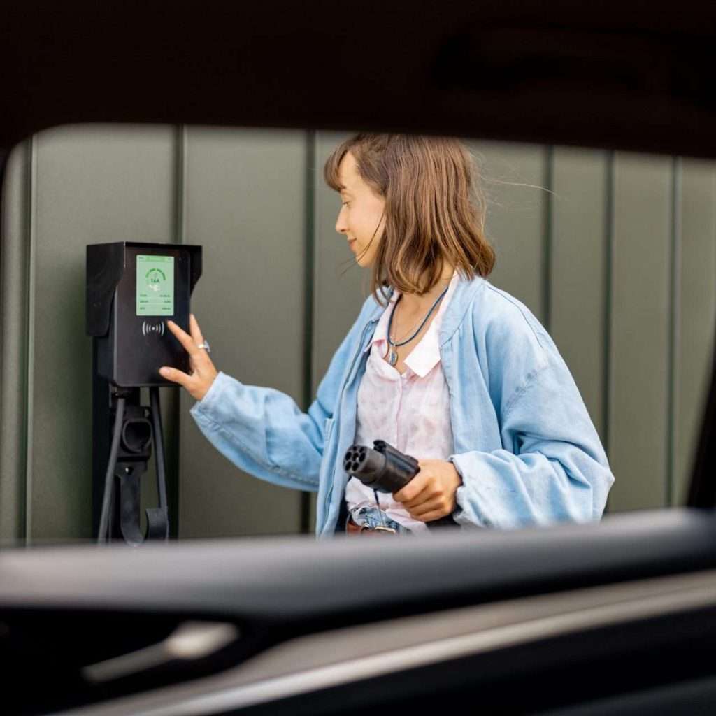 A woman looking about to plug in her electric vehicle. This is a title image for our RTS Academy course on EV Ownership