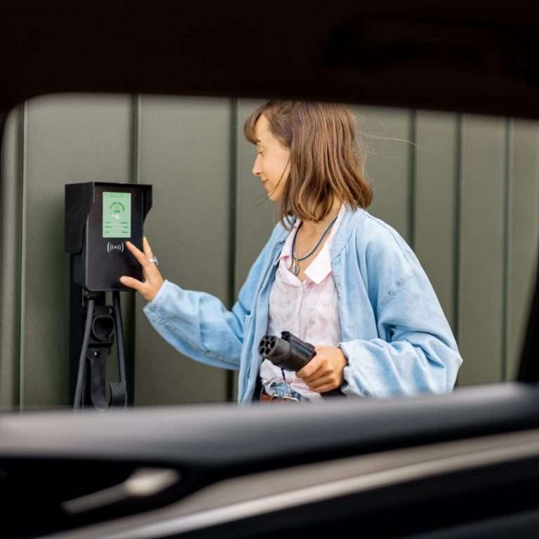 A woman looking about to plug in her electric vehicle. This is a title image for our RTS Academy course on EV Ownership