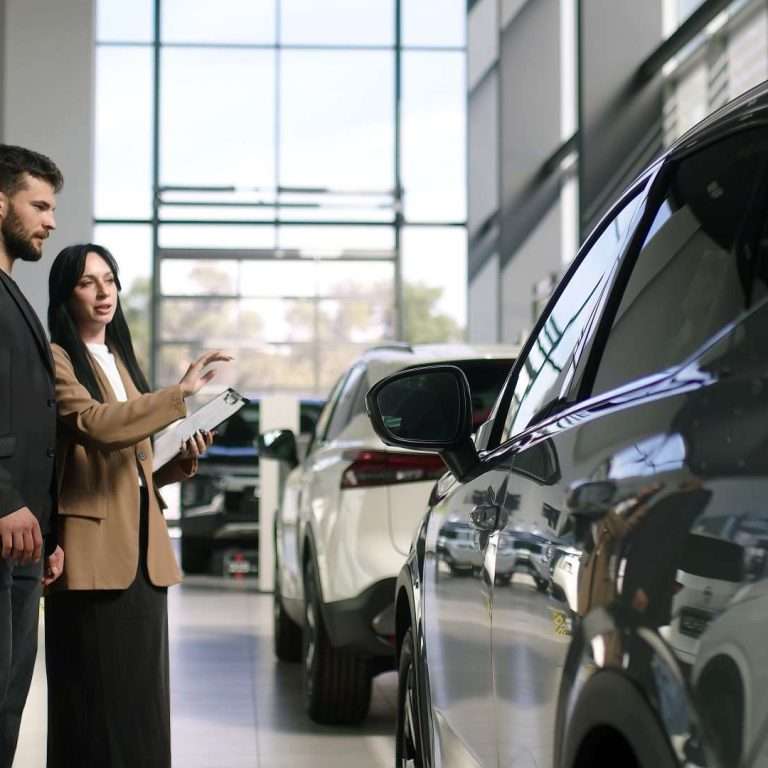 A automotive dealership. Two people are looking at a car. This course focuses on electric vehicles for RTS Academy.