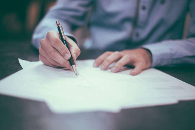 A man signing a document, representing a contract being signed. For the Automotive Legislation Course via RTS Academy.