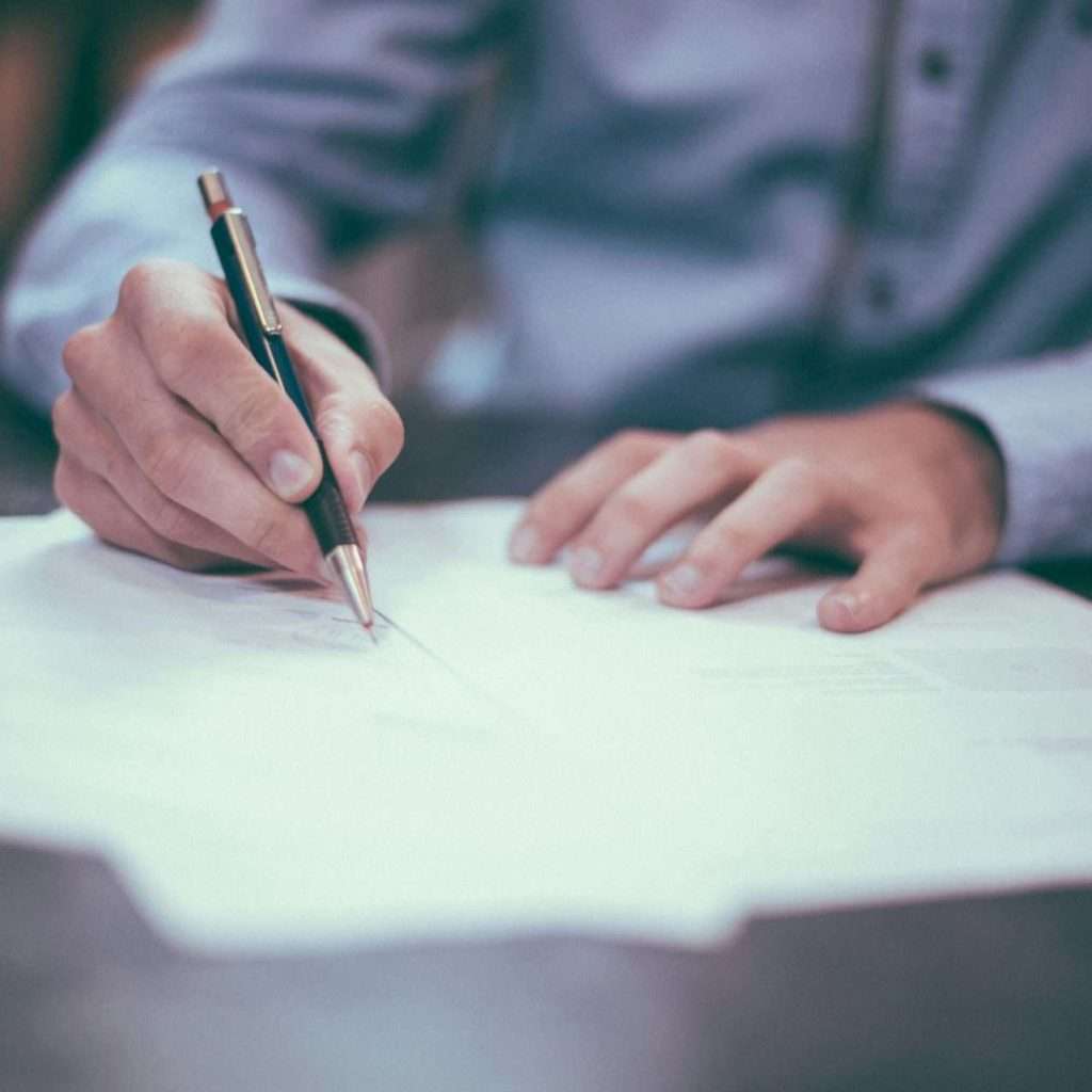 A man signing a document, representing a contract being signed. For the Automotive Legislation Course via RTS Academy.