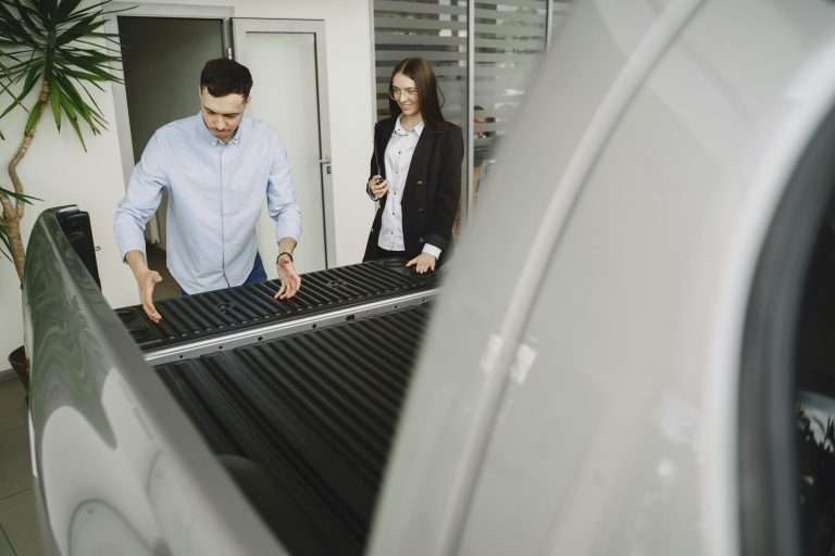 A salesperson showing a prospective customer the features of a vehicle in a dealership. For the "product demonstration" course via RTS Academy.