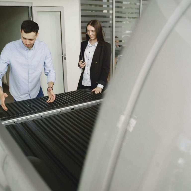 A salesperson showing a prospective customer the features of a vehicle in a dealership. For the "product demonstration" course via RTS Academy.