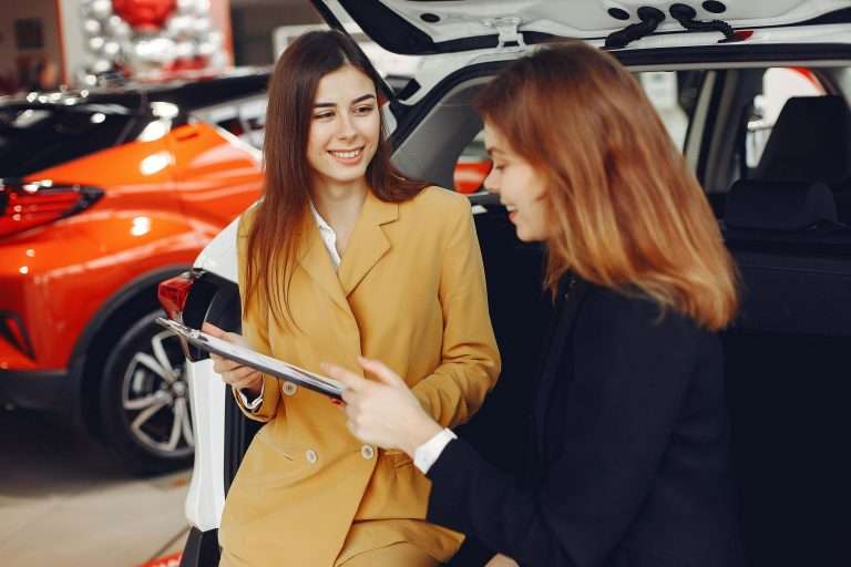 Two women at a dealership. Saleswoman and prospective customer. Representing lead generation and the associated processes. For RTS Academy.