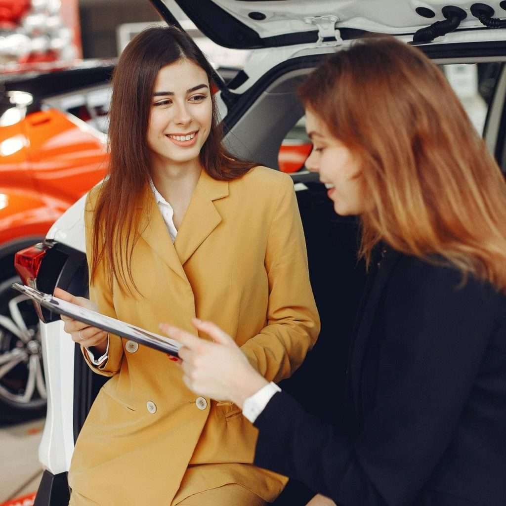 Two women at a dealership. Saleswoman and prospective customer. Representing lead generation and the associated processes. For RTS Academy.
