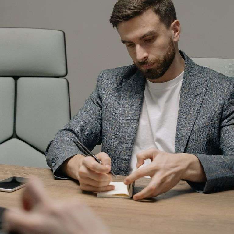 A businessman writing notes during a meeting, showcasing focus and professionalism.