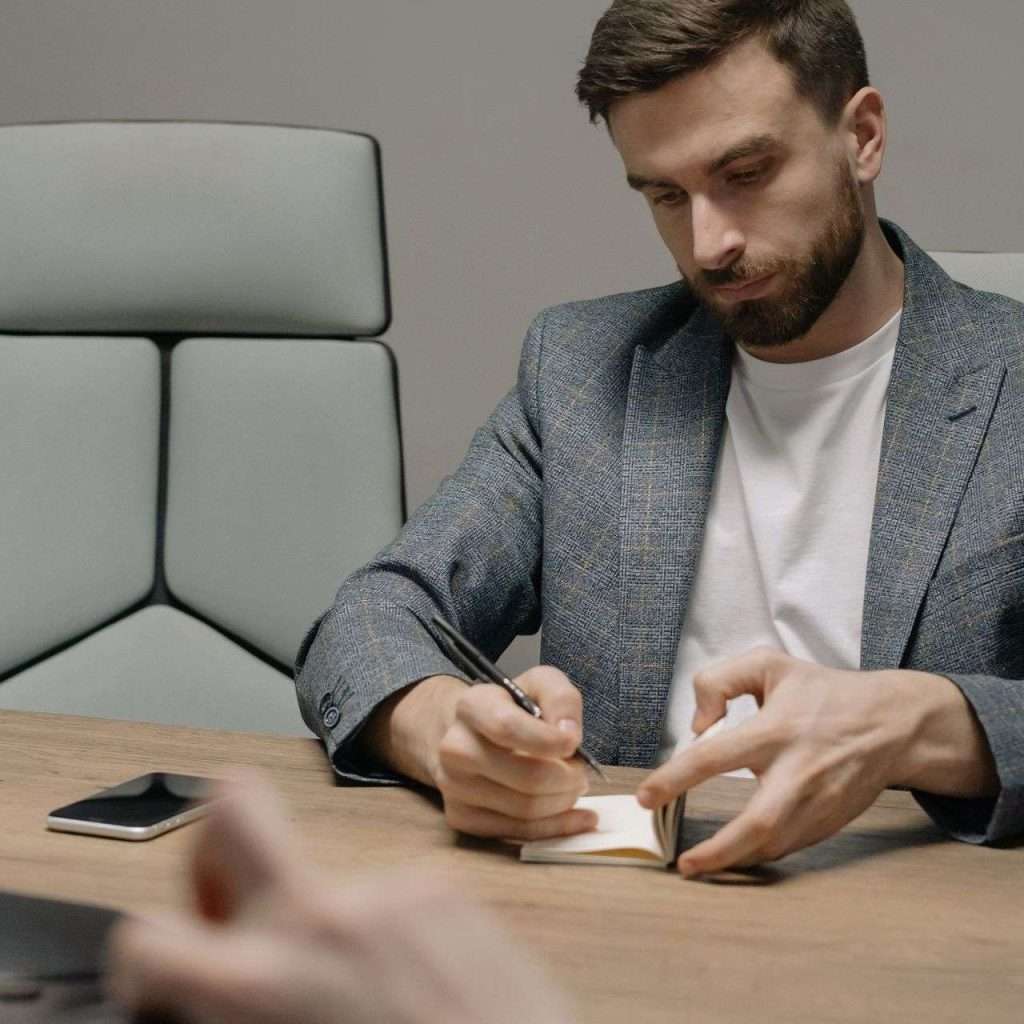 A businessman writing notes during a meeting, showcasing focus and professionalism.
