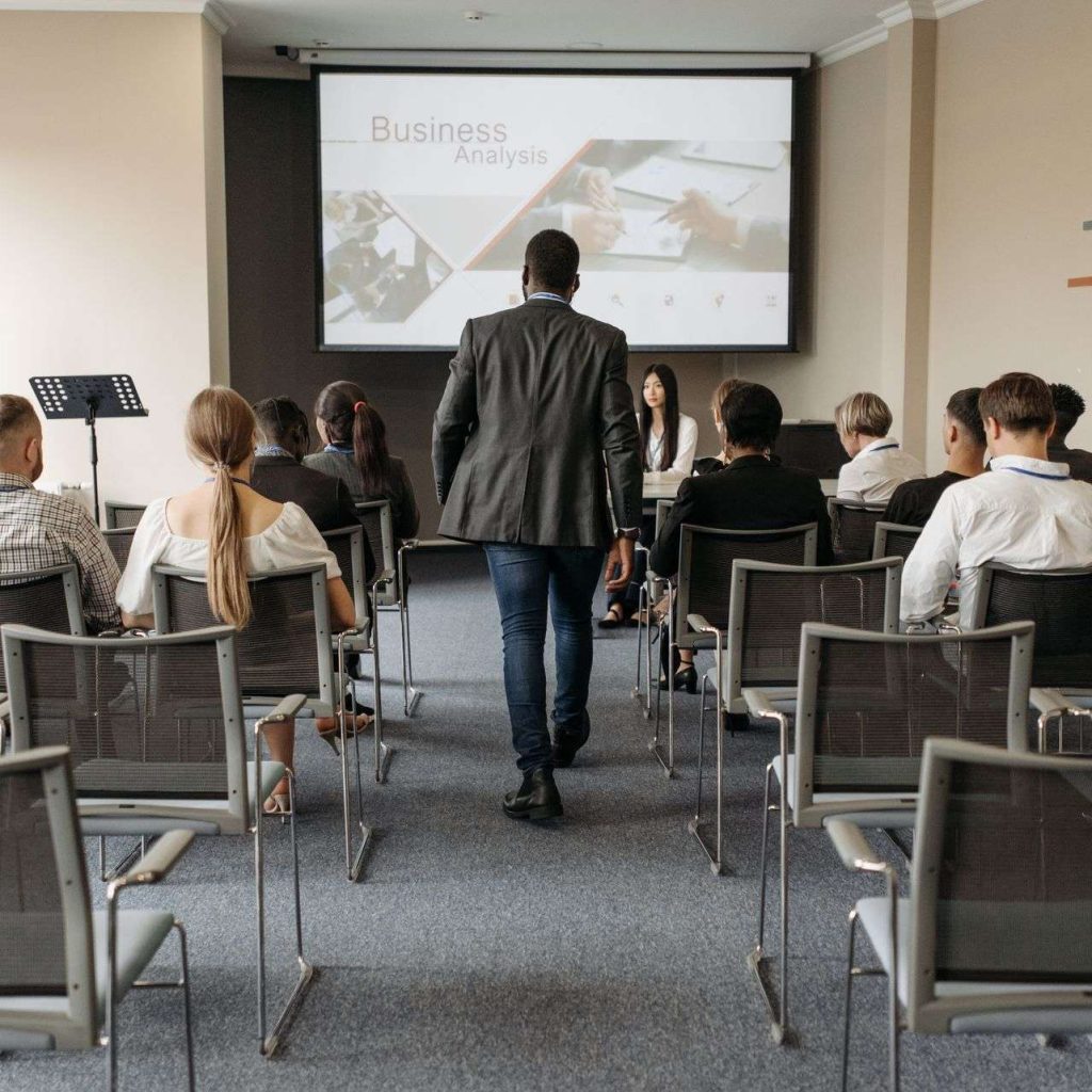 Business conference setting with diverse participants focusing on analysis presentation.