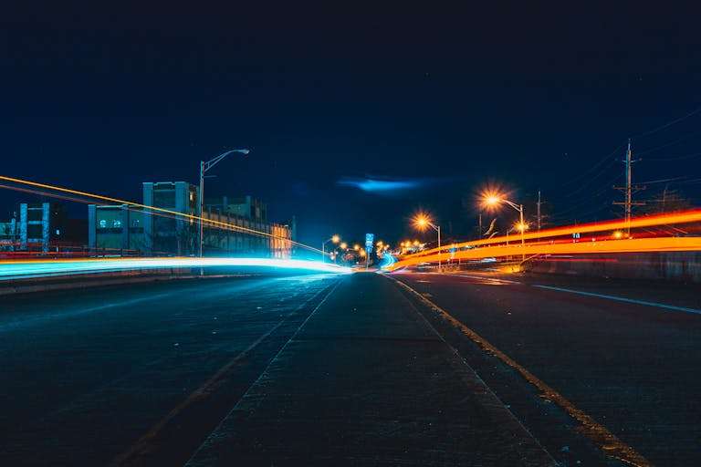 Captivating night cityscape with vibrant light trails on an urban highway, showcasing dynamic movement and city lights for the RTS Academy electric vans eLearning module.