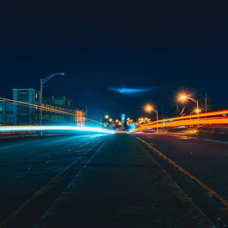 Captivating night cityscape with vibrant light trails on an urban highway, showcasing dynamic movement and city lights for the RTS Academy electric vans eLearning module.