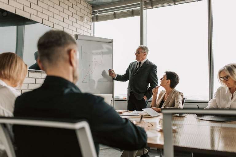 Senior leader presenting growth charts in a business meeting with colleagues in a modern office setting.
